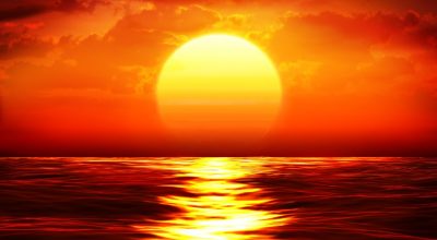 A photo of the sun setting over water.