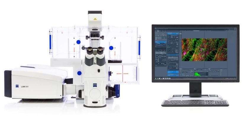 An inverted Zeiss microscope with incubation chamber and a LSM 880 scanhead on the left port are shown to the left, and to the right an example monitor with ZEN software is shown.