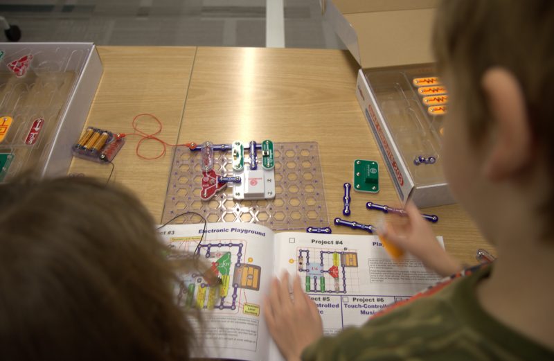 Looking down on two children playing with circuit kits as part of the Fralin Life Scienced Institute's STEM homeschooling club. 