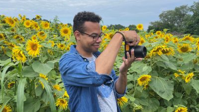 Joseph Taylor aims his camera toward a field of sunflowers.