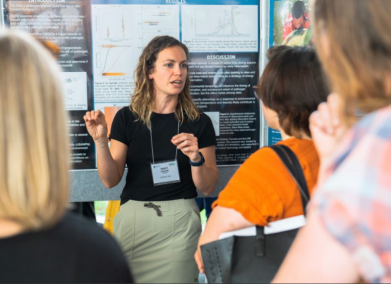 Macy Kailing talks about her research at a poster symposium.