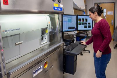 The image shows Melissa Makris using the flow cytometer.