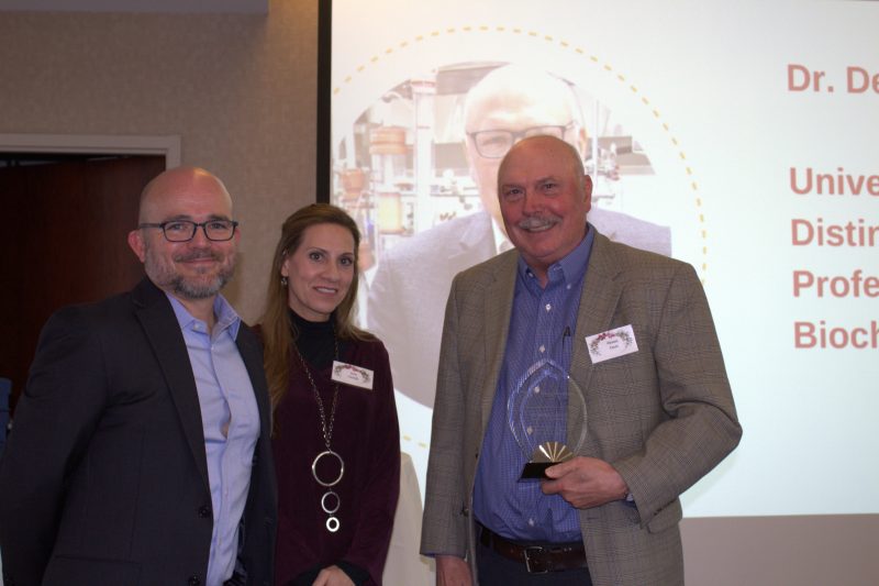Bill Hopkins, at left, and Erin Cassidy, center, present the inaugural 2022 Lifetime Achievement Award to Dennis Dean, University Distinguished Professor of Biochemistry